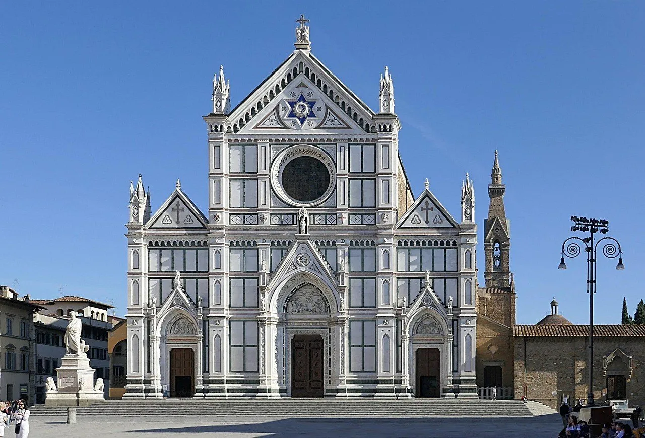 Fachada de mármore da Basílica de Santa Croce sob céu azul, com estátua de Dante à esquerda.