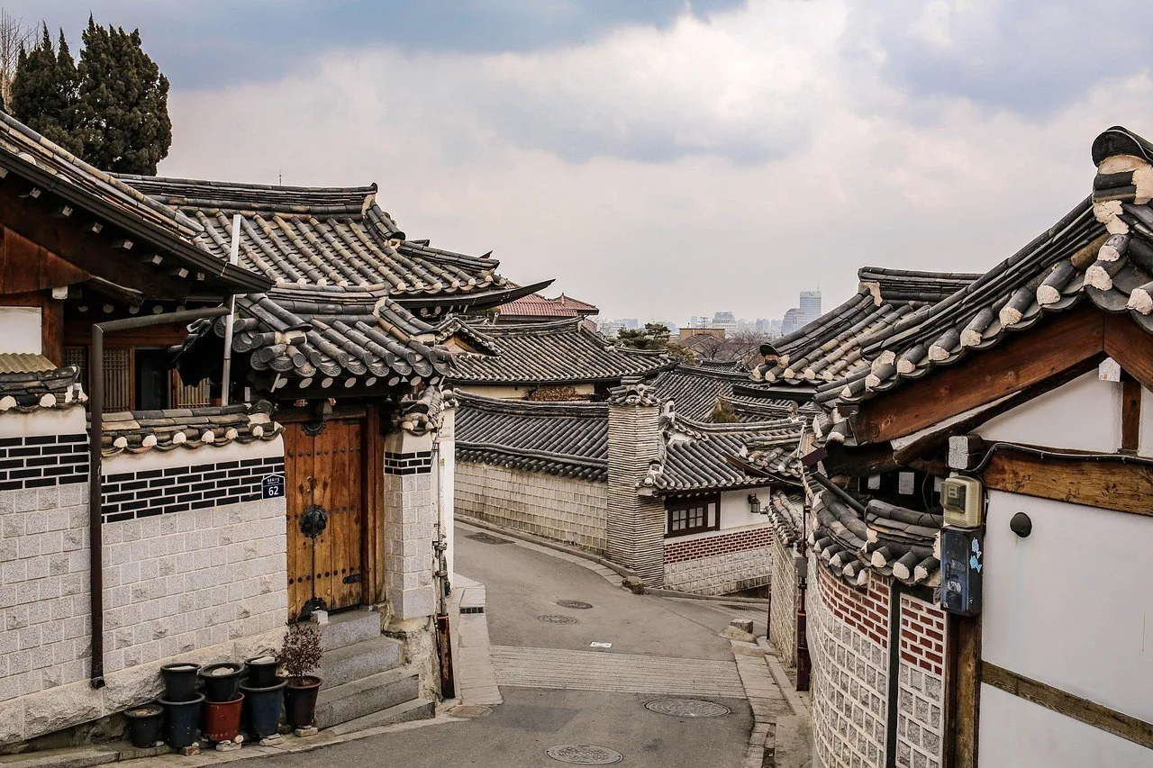 Rua inclinada de Bukchon com casas hanok, muros de tijolos e telhados curvos.