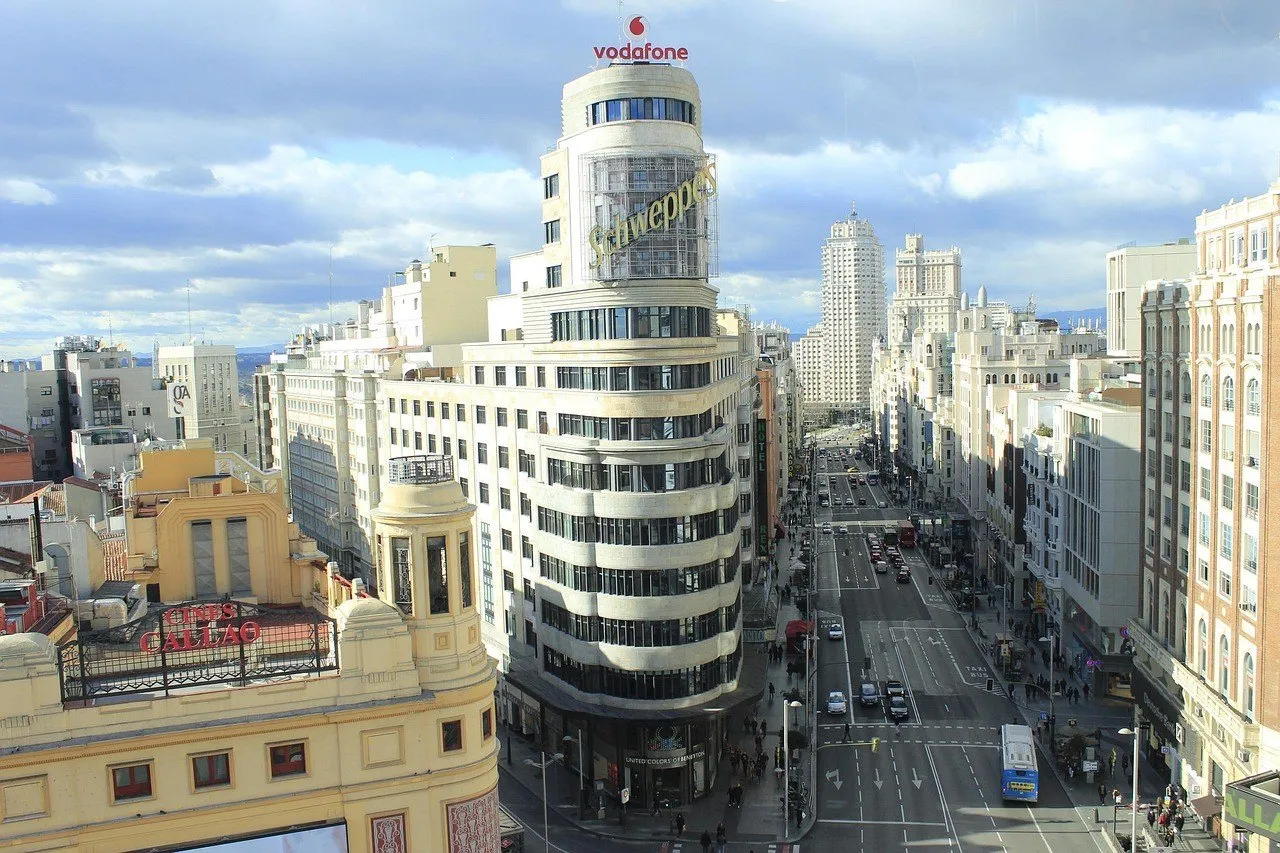 Edifício Capitol e Gran Vía vistos de cima, com fachadas claras sob céu parcialmente nublado.