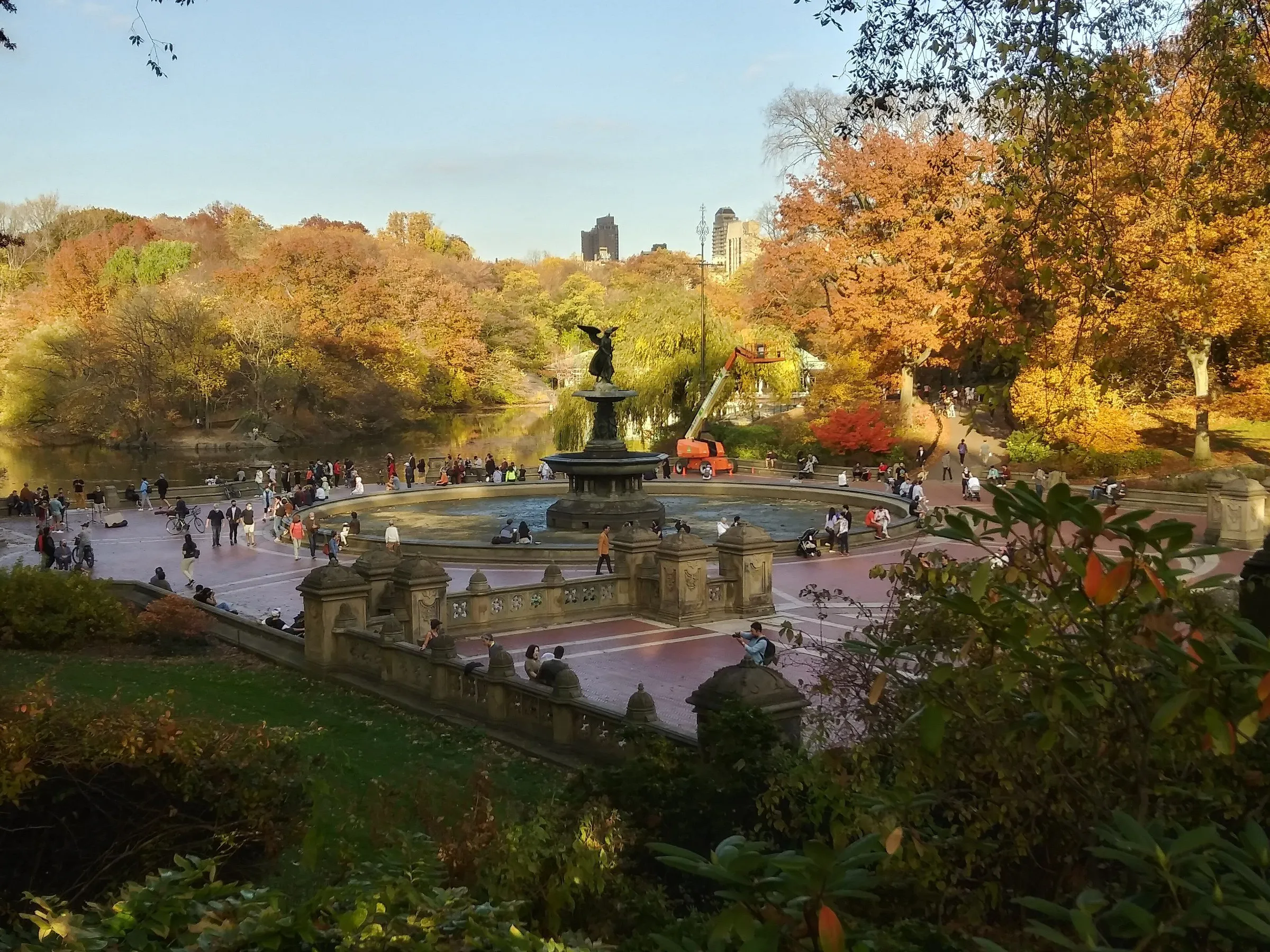 Fonte de Bethesda com a estátua do anjo ao lado do lago do Central Park, cercada de árvores de folhas alaranjadas no outono.