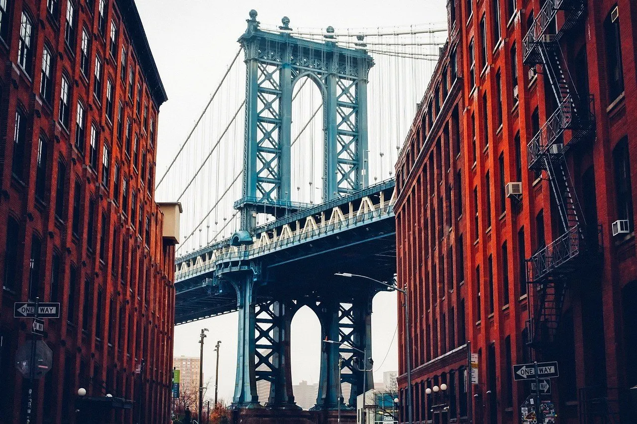 Torre da Ponte de Manhattan vista entre dois prédios de tijolo vermelho com escadas de incêndio, numa rua do DUMBO.