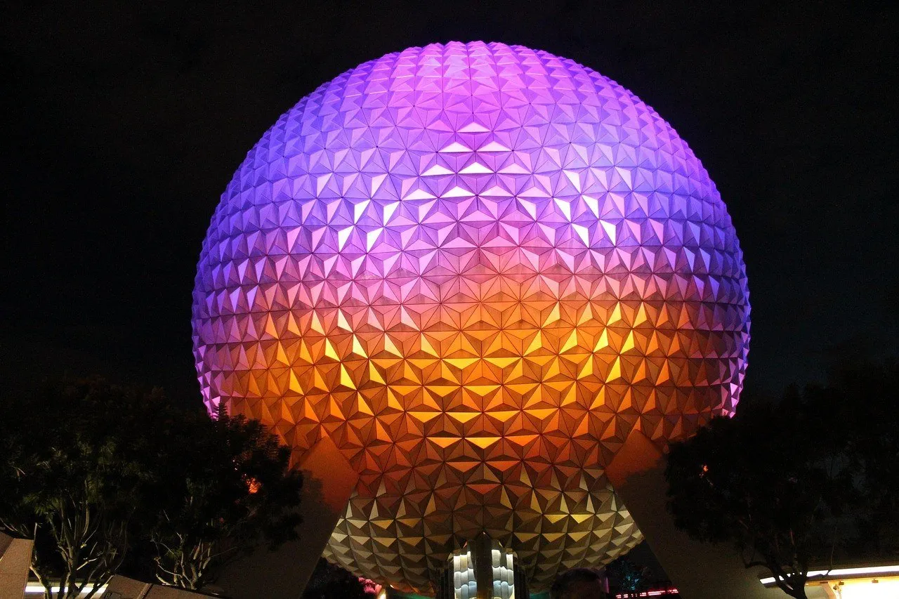 Esfera Spaceship Earth iluminada em roxo e laranja à noite no EPCOT, na Flórida.