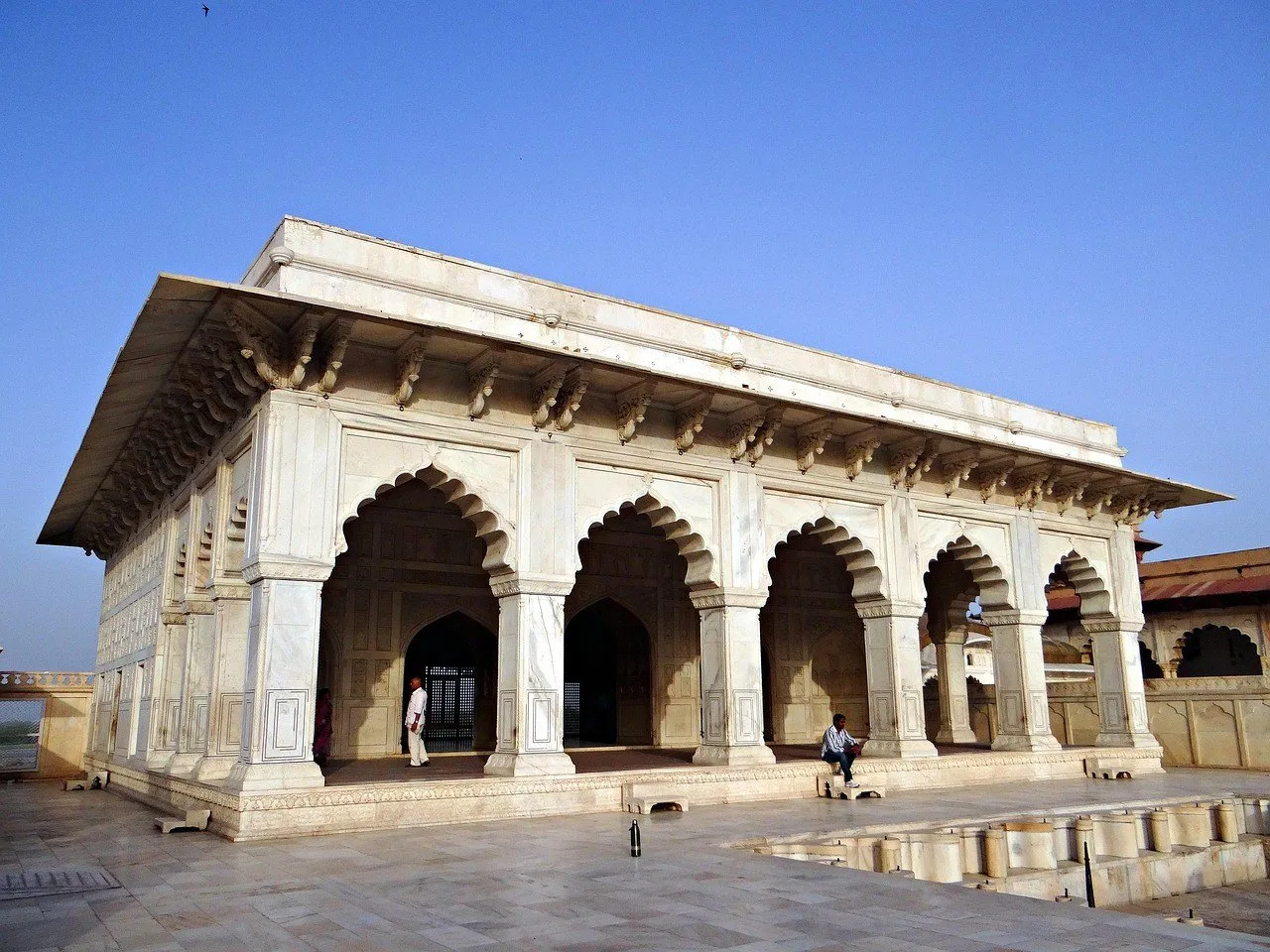 Pavilhão de mármore branco com arcos no Forte de Agra, sob céu azul.