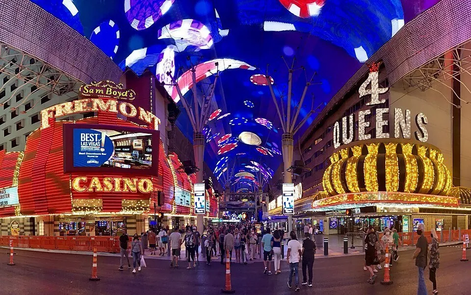 Cobertura de LED azul da Fremont Street, entre os letreiros dos cassinos Fremont e Four Queens e pedestres.