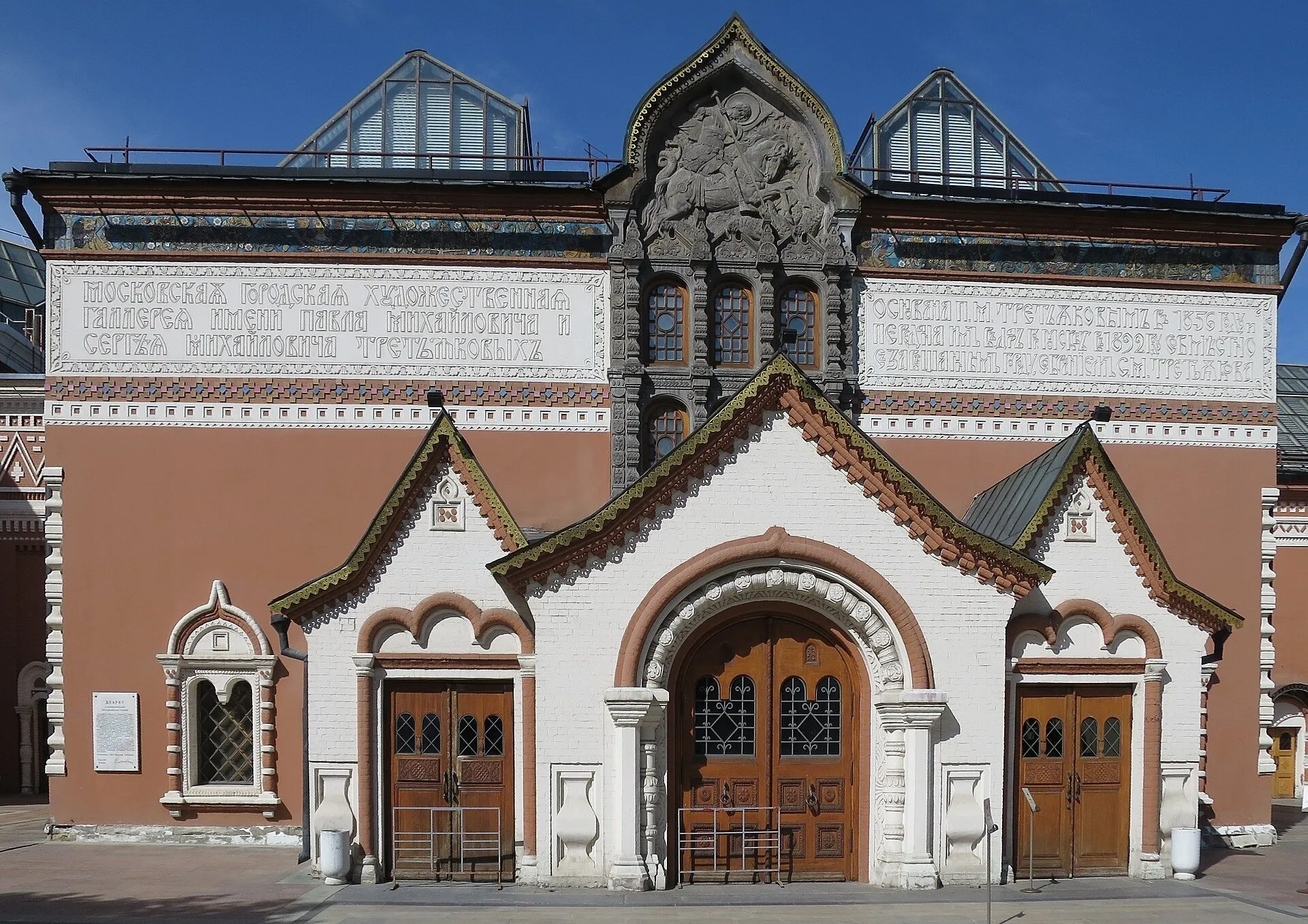 Fachada ornamentada da Galeria Tretyakov em Lavrushinsky, com portas de madeira, inscrições e céu azul.