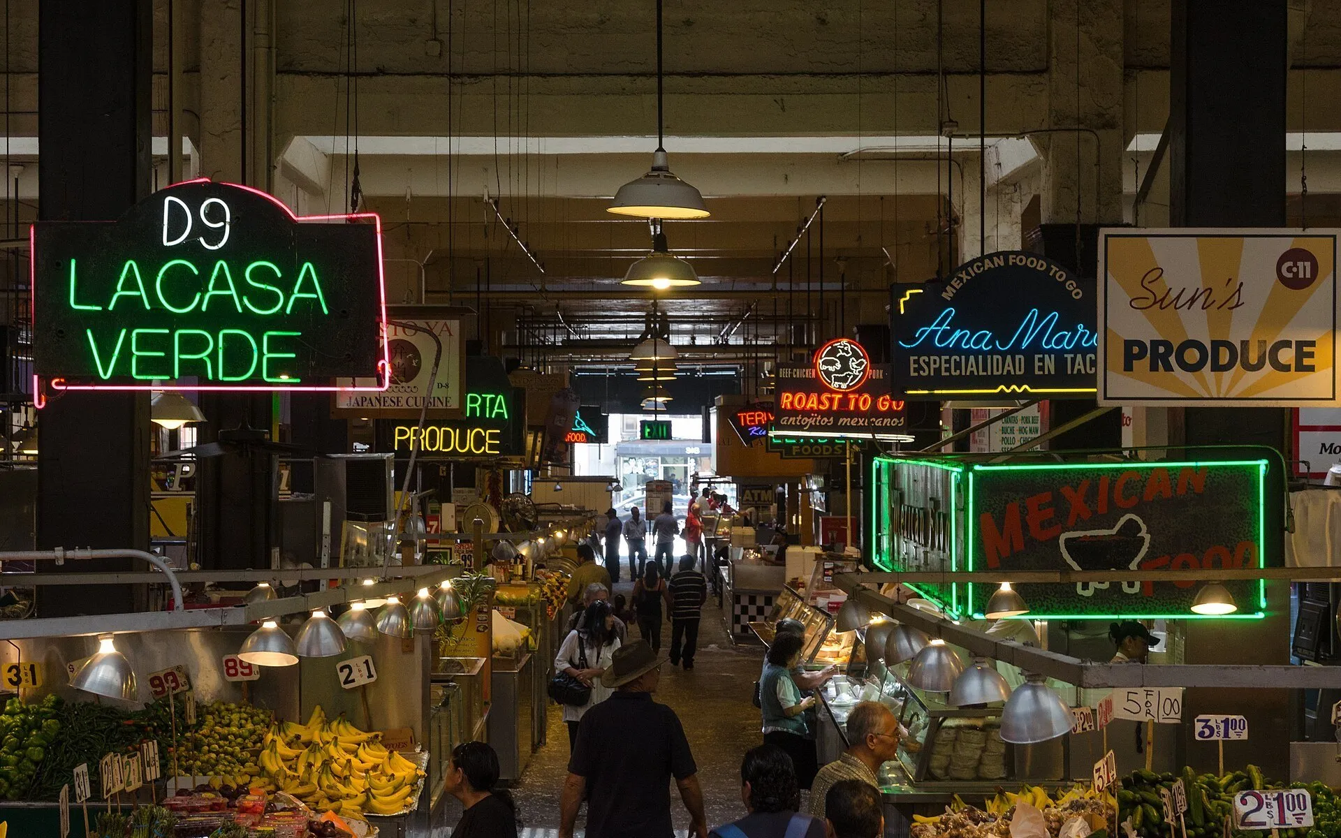 Letreiros de néon, balcões de frutas e visitantes no interior do Grand Central Market, em Los Angeles.