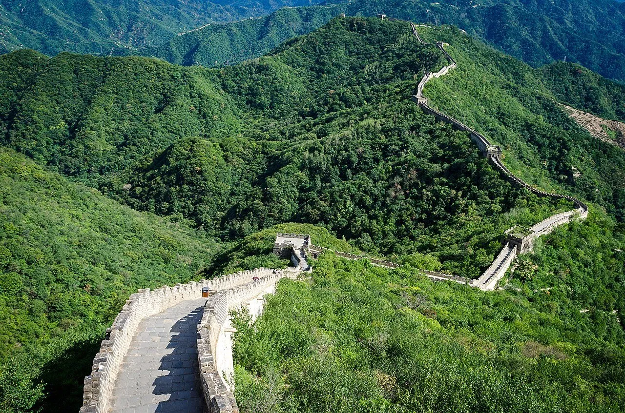 Grande Muralha em Mutianyu serpenteando entre montanhas cobertas de vegetação verde.