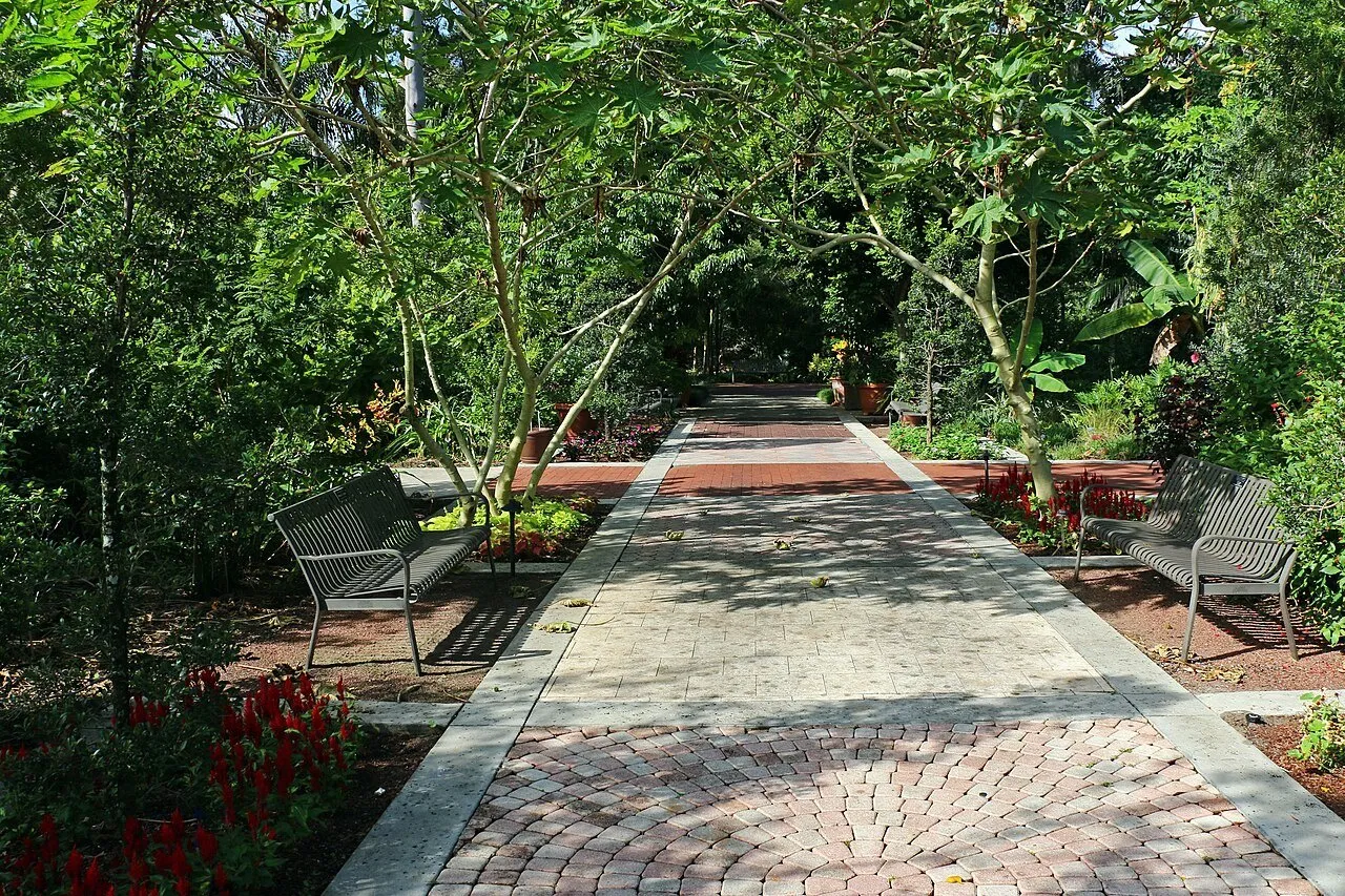 Caminho pavimentado entre árvores, flores e bancos nos Harry P. Leu Gardens, em Orlando.
