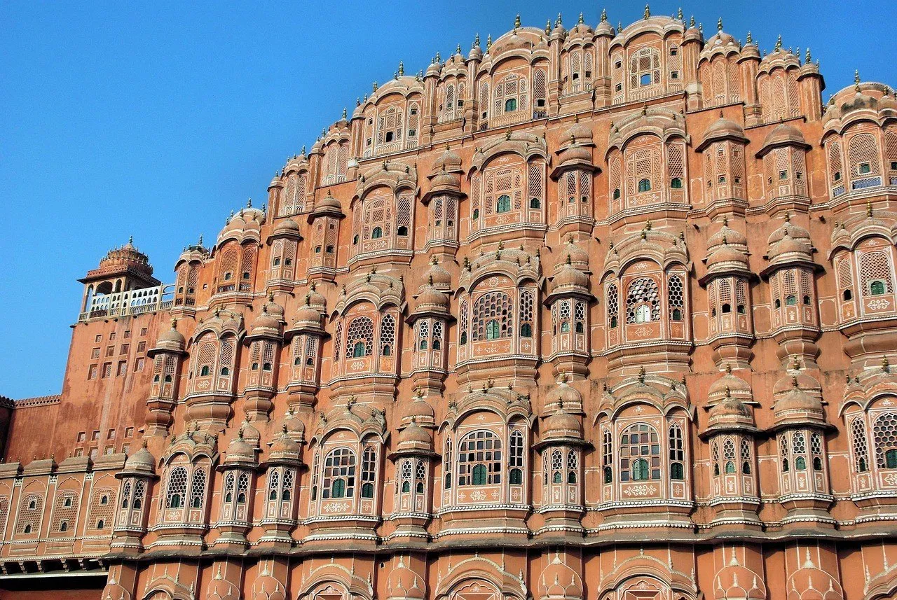 Fachada do Hawa Mahal vista em diagonal de baixo, com pequenas varandas e céu azul.