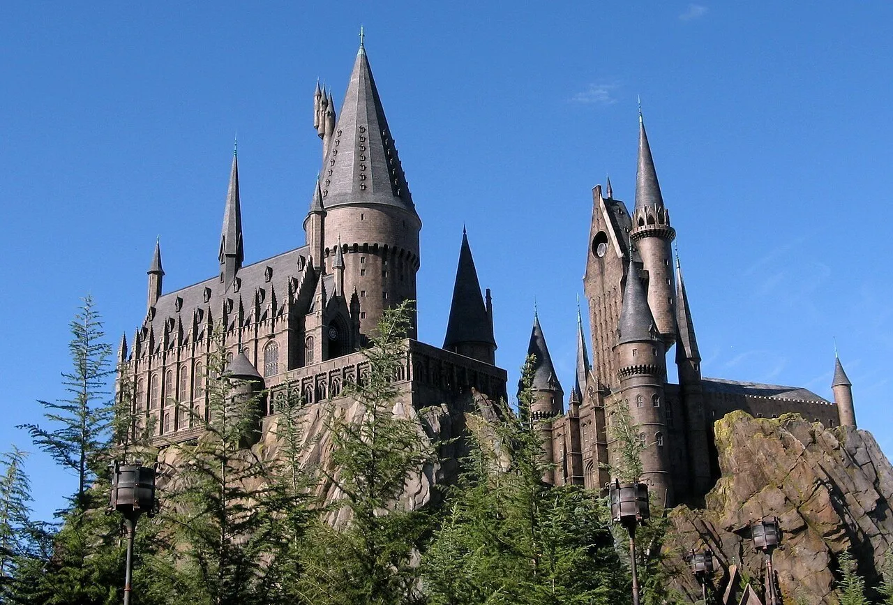 Castelo de Hogwarts sobre rochas e árvores no Islands of Adventure, em Orlando, sob céu azul.