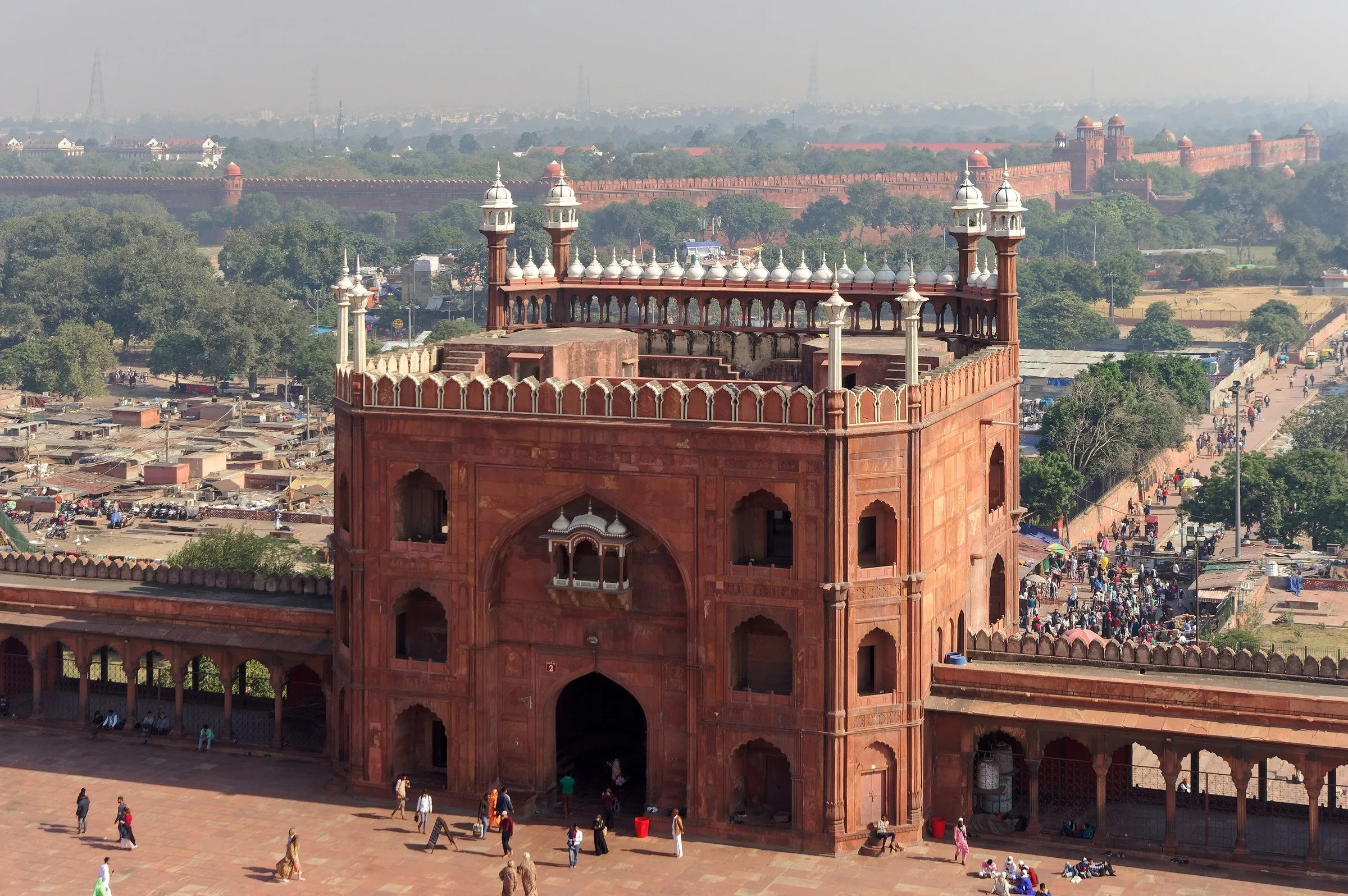 Portão leste da Jama Masjid, em Délhi, visto do alto, com o pátio embaixo e as muralhas do Forte Vermelho ao fundo.