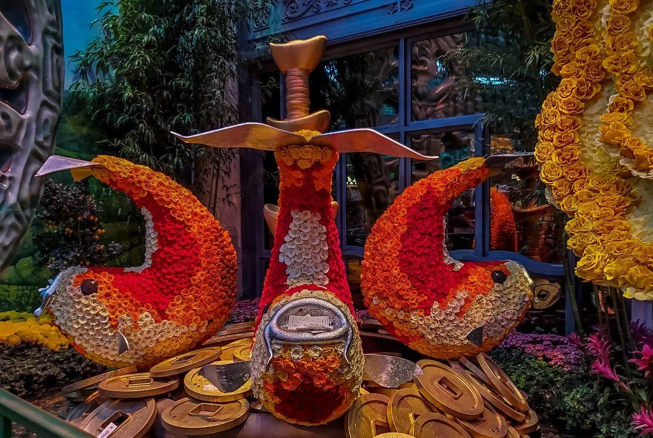 Peixes decorativos vermelhos e laranjas feitos de flores, entre moedas cenográficas no Conservatory do Bellagio.