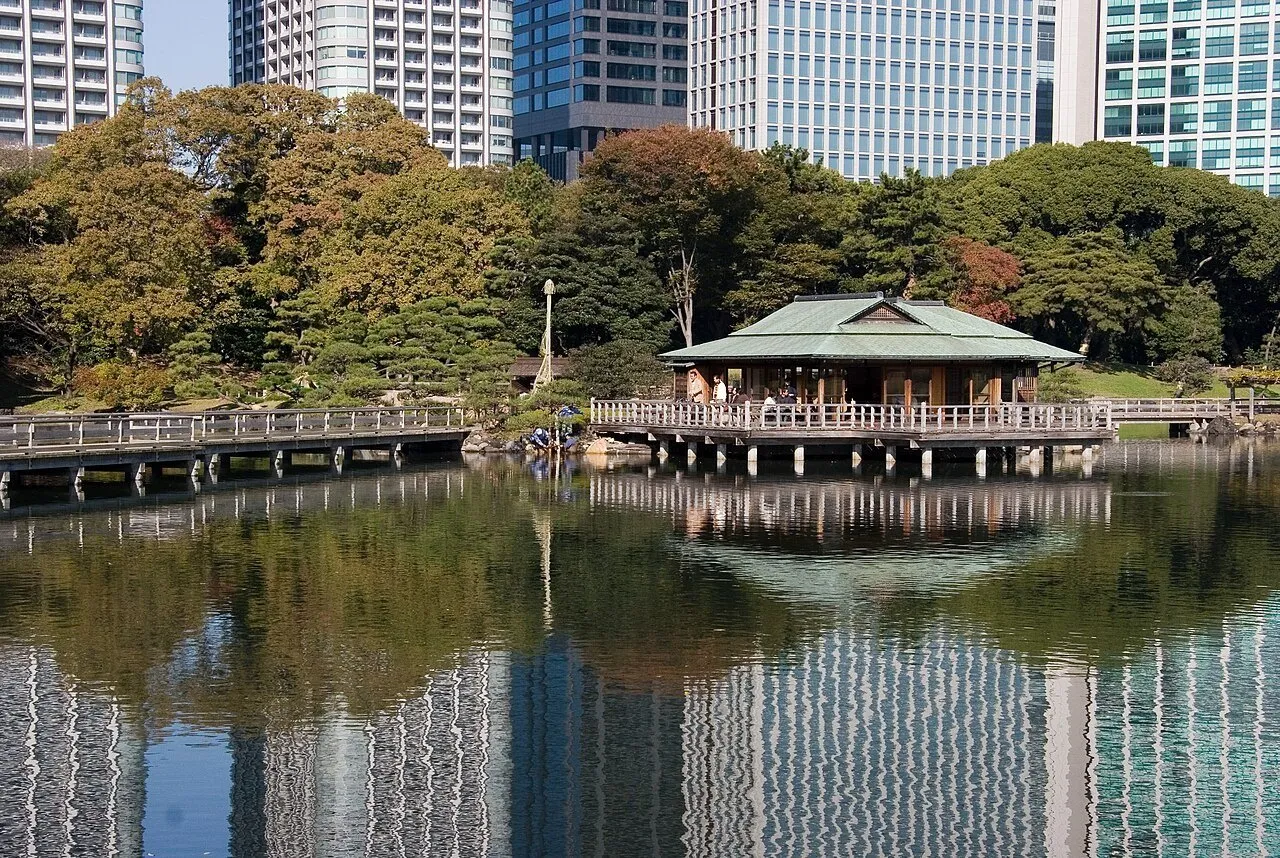 Casa de chá sobre o lago de Hamarikyu, com árvores e arranha-céus de Shiodome refletidos na água.