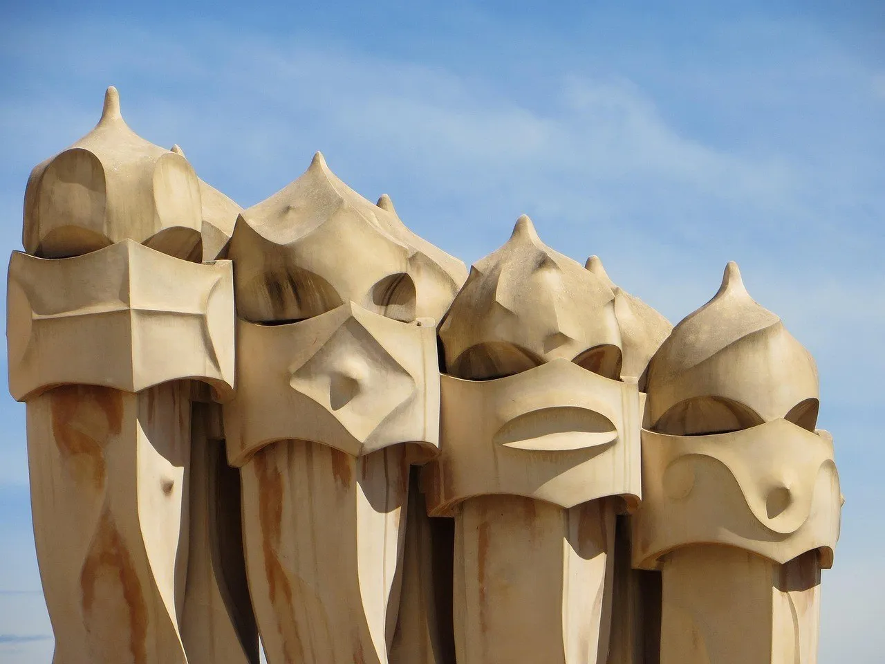 Grupo de chaminés escultóricas de pedra clara na cobertura de La Pedrera, sob céu azul.