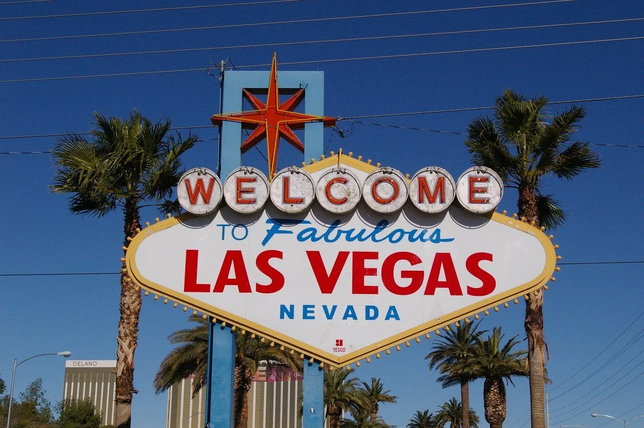 Letreiro Welcome to Fabulous Las Vegas inteiro entre palmeiras, sob céu azul.