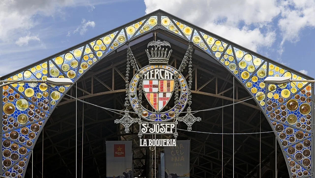 Frontão de ferro e vidros coloridos na entrada da Boqueria, com brasão e letreiro Sant Josep.