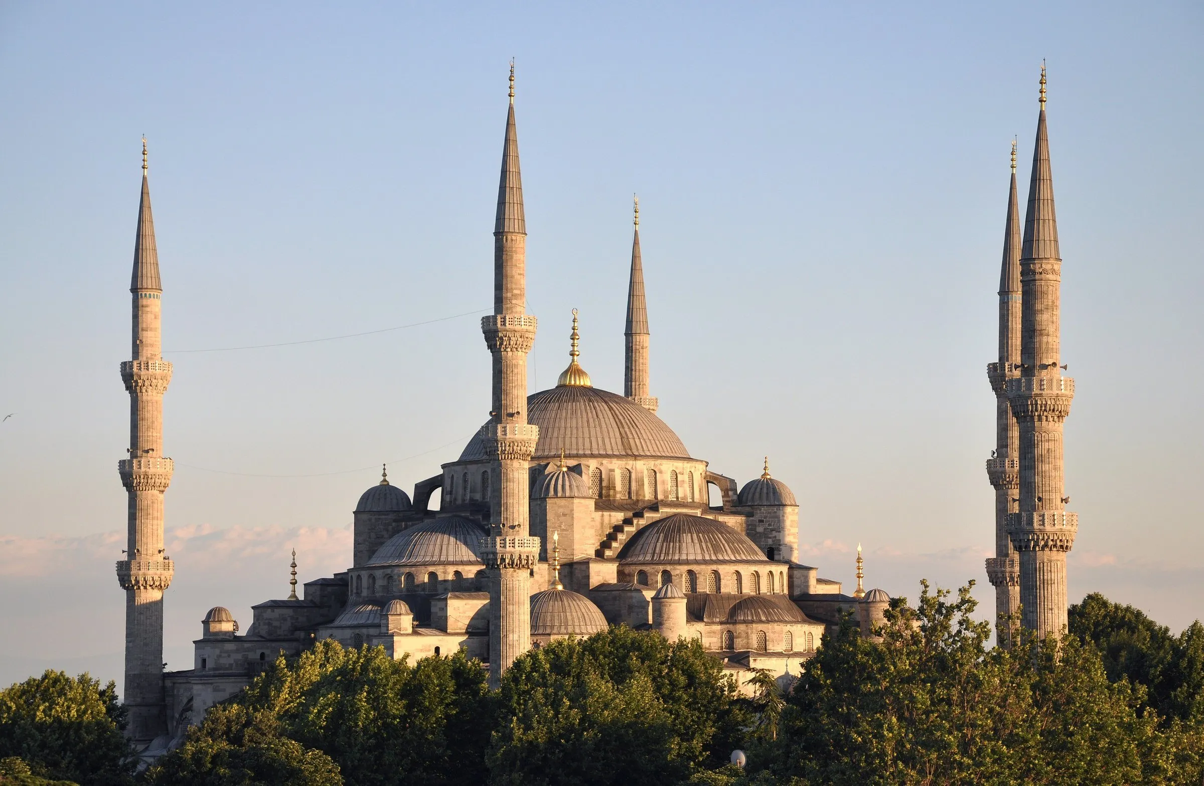 Mesquita do Sultão Ahmed vista de fora, com seis minaretes e várias cúpulas escalonadas, iluminada pelo sol baixo.