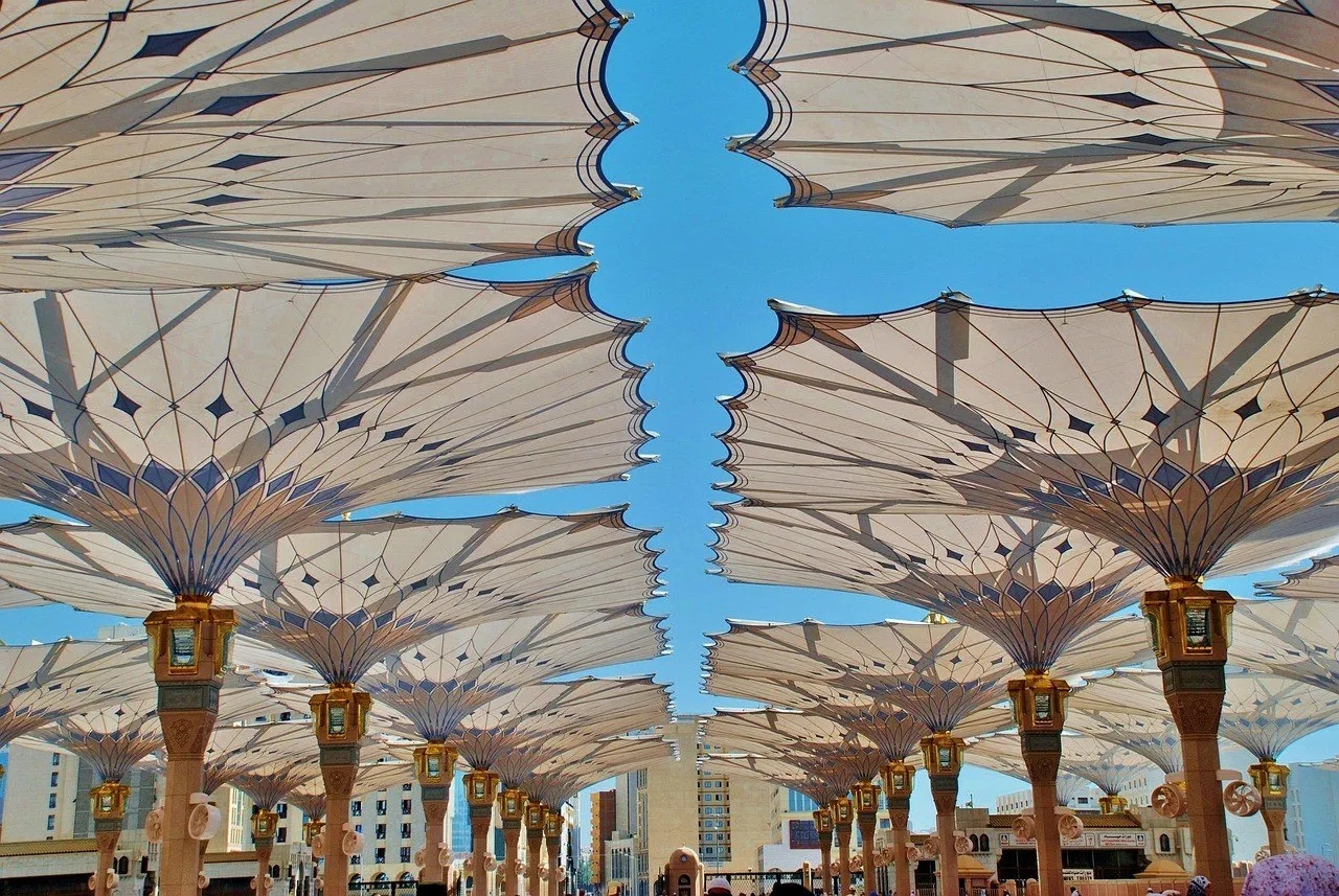 Coberturas abertas em forma de guarda-sol nos pátios da Mesquita do Profeta, sob céu azul.