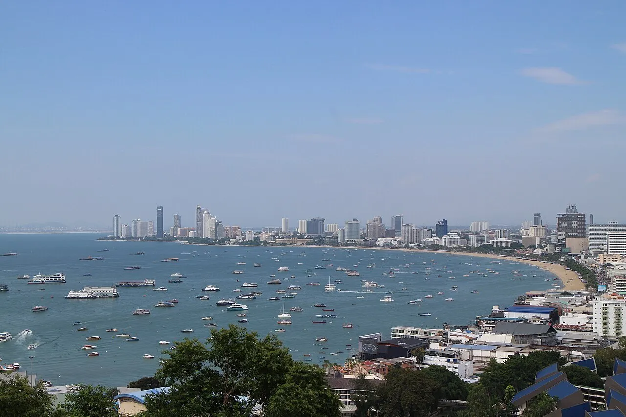 Baía de Pattaya vista do alto de Pratumnak, com barcos, praia curva e prédios da orla ao fundo.