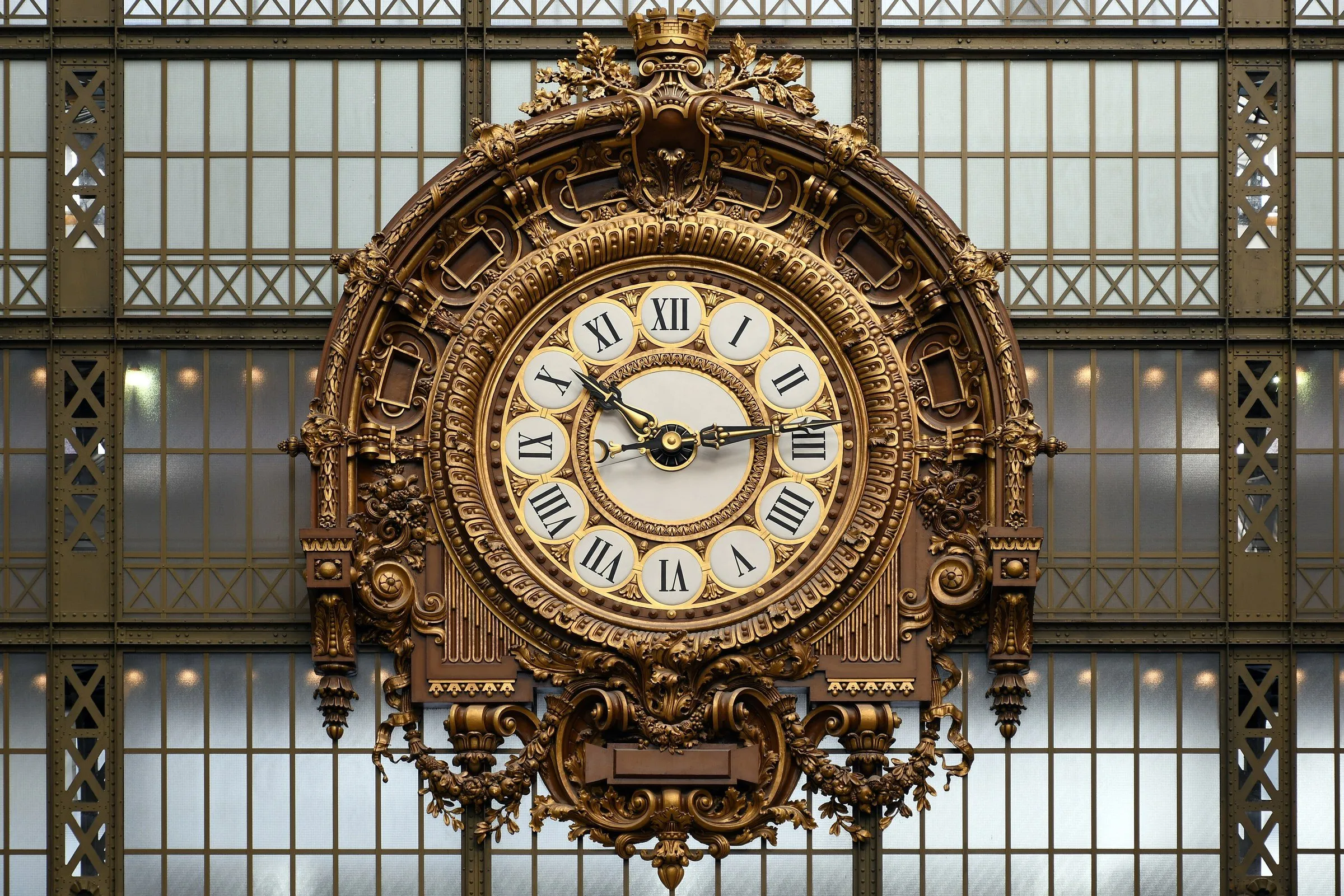 Relógio dourado de algarismos romanos preso à vidraça de ferro da antiga estação, hoje Museu d'Orsay.