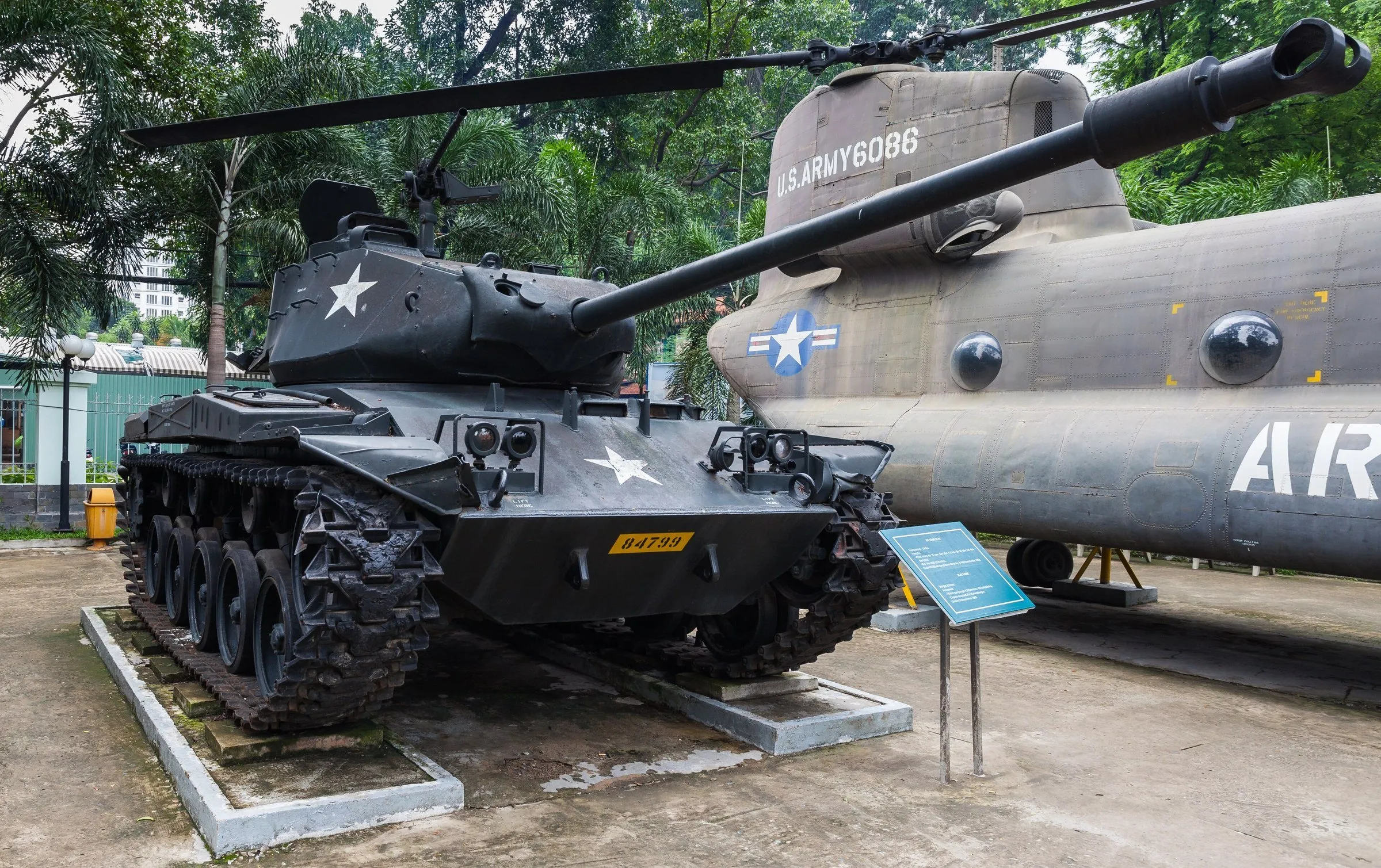 Tanque escuro e helicóptero militar expostos ao ar livre no Museu dos Vestígios da Guerra.