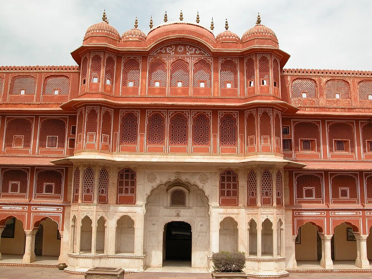 Fachada rosada com janelas de treliça e arcos de mármore em um pátio do Palácio da Cidade de Jaipur.