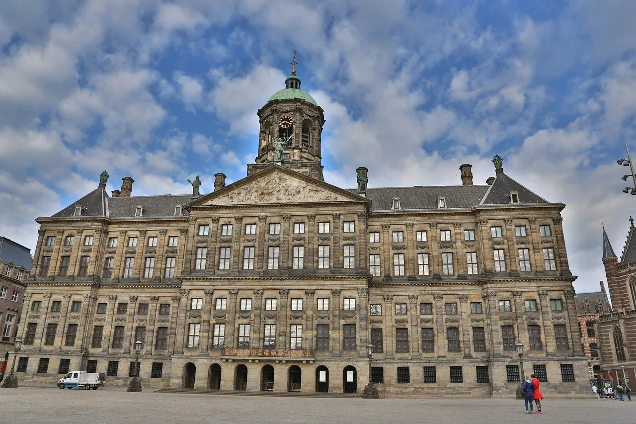 Fachada de pedra do Palácio Real de Amsterdã, com torre do relógio, diante da Praça Dam.
