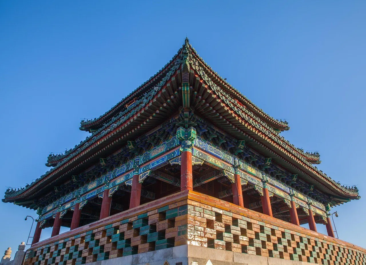 Pavilhão Wanchun, no Parque Jingshan, visto de baixo sob céu azul, com colunas vermelhas.
