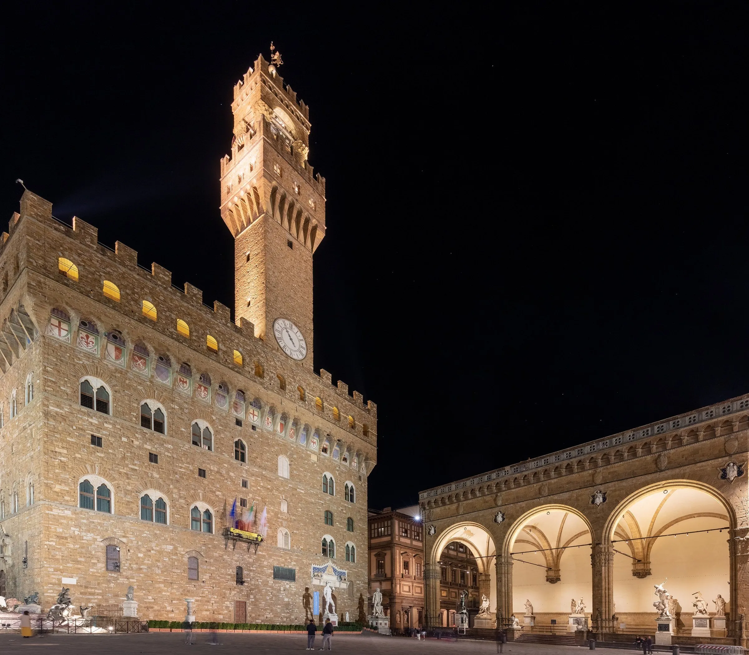 Palazzo Vecchio e esculturas da Loggia dei Lanzi iluminados à noite na Piazza della Signoria.