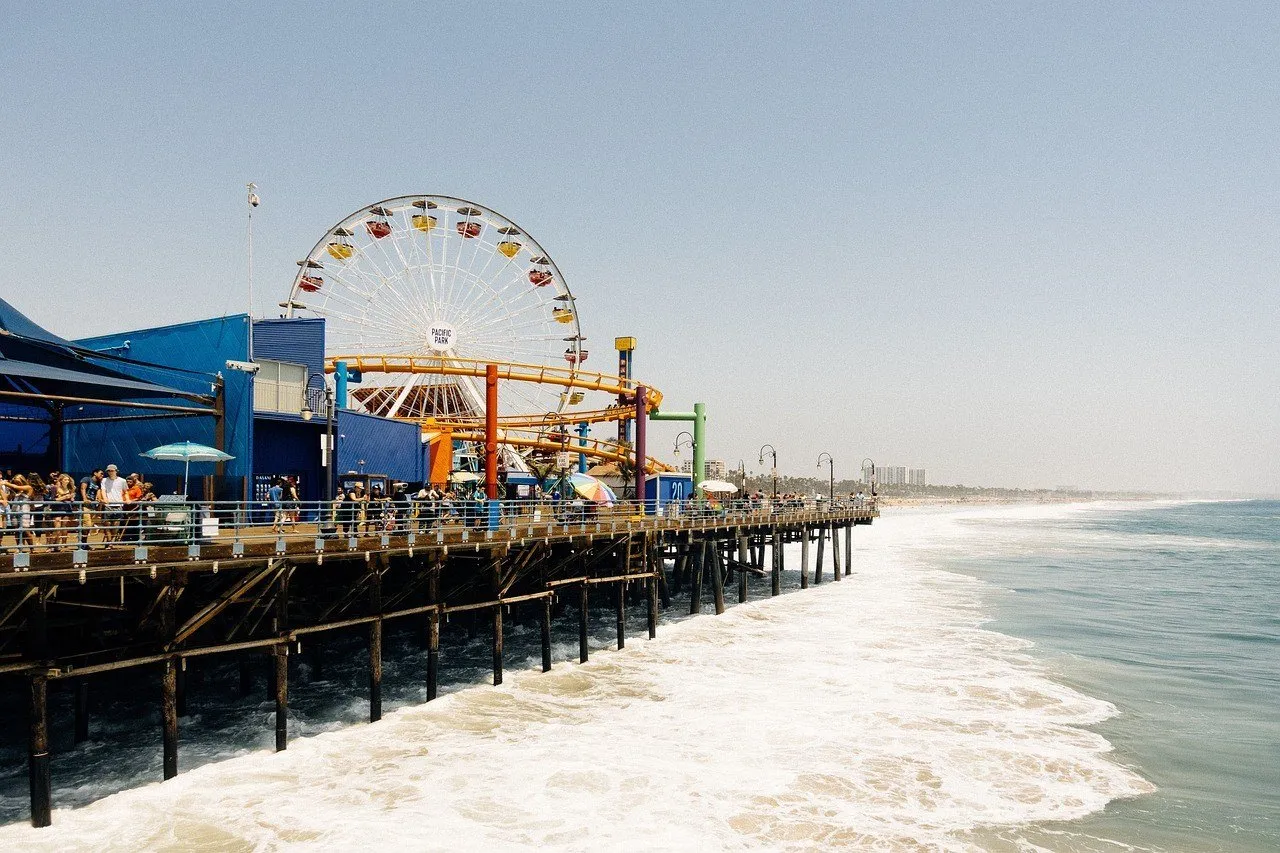 Píer de Santa Monica visto de lado, com roda-gigante e ondas do Pacífico sob a estrutura.