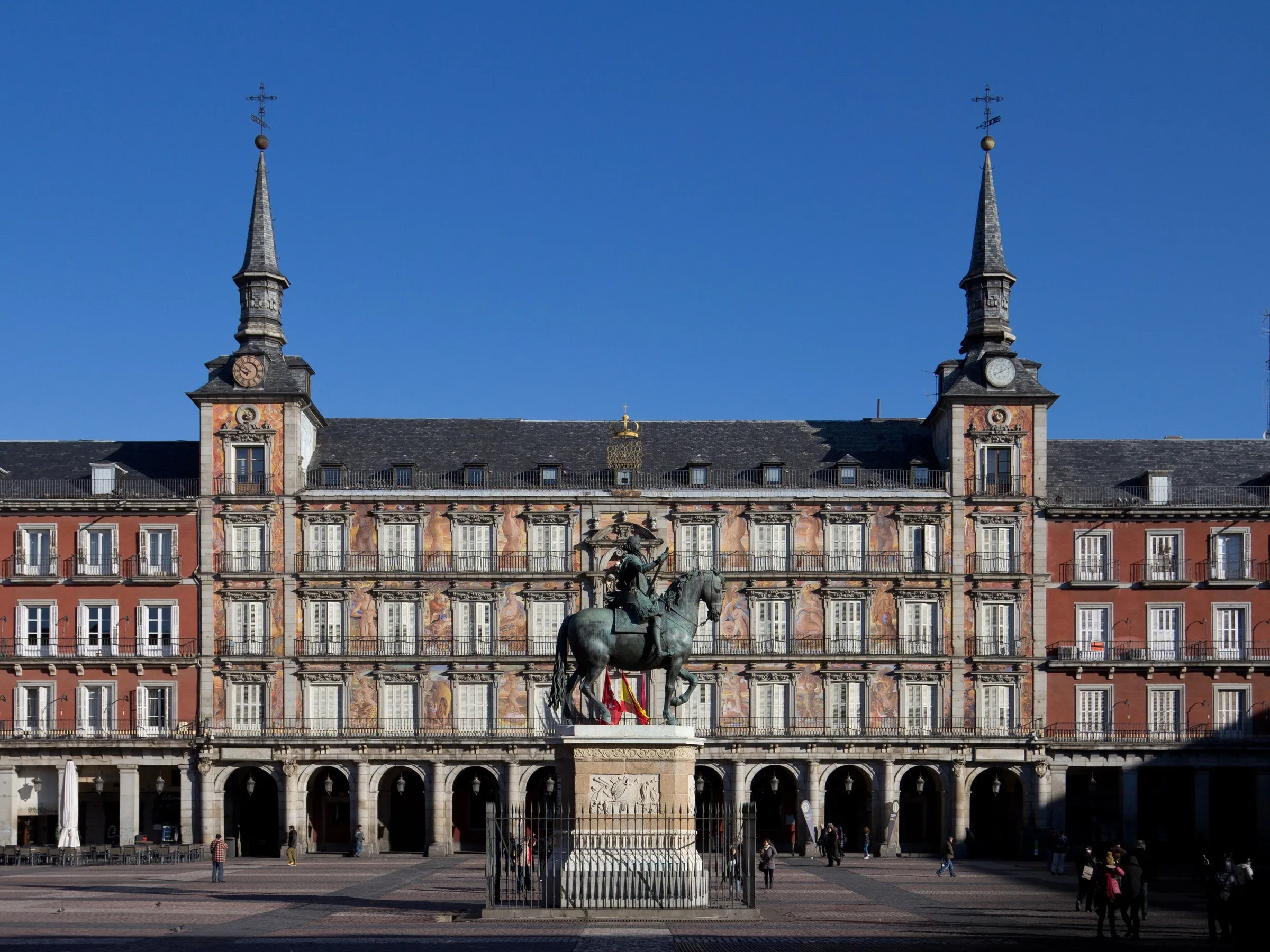 Casa de la Panadería, com duas torres e murais, atrás de uma estátua equestre na Plaza Mayor.