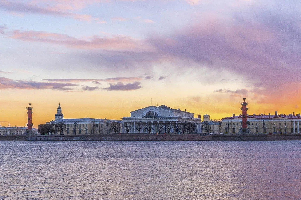 Antiga Bolsa e duas colunas rostrais na Ilha Vassilievski, vistas do Neva sob céu rosado.