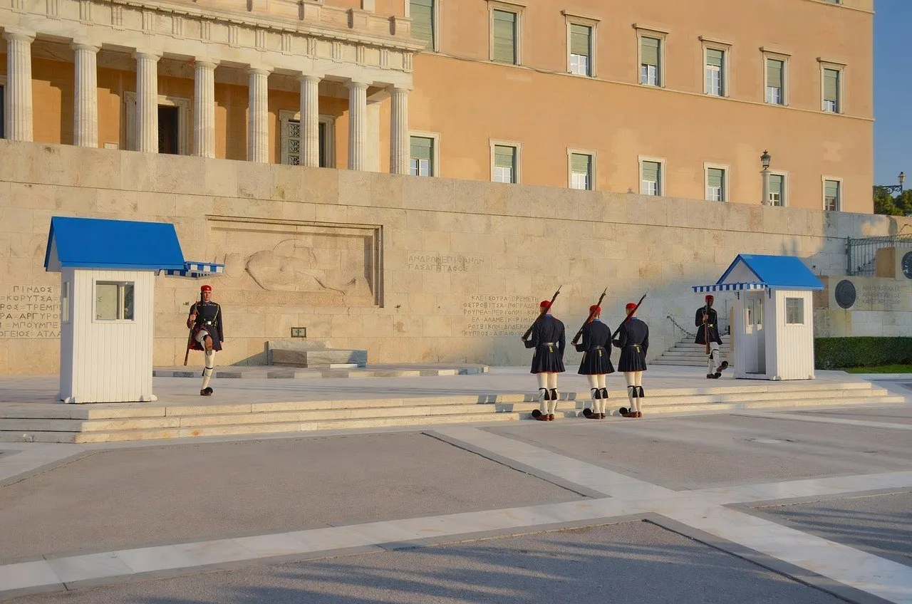 Evzones em cerimônia diante do Túmulo do Soldado Desconhecido e da fachada do Parlamento em Atenas.