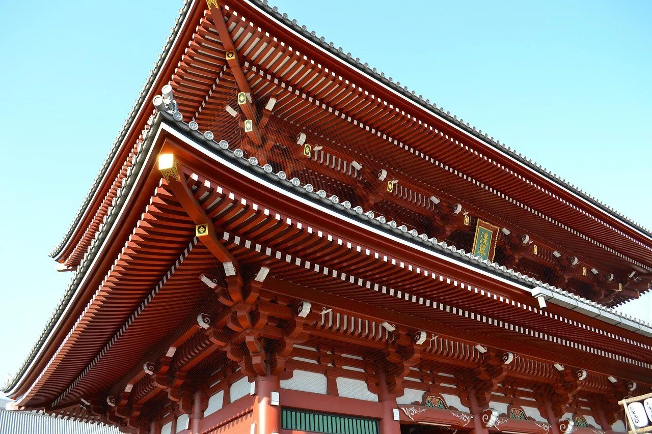 Beirais vermelhos em camadas do portão Hozomon, no templo Senso-ji, em Tóquio, contra um céu azul sem nuvens.