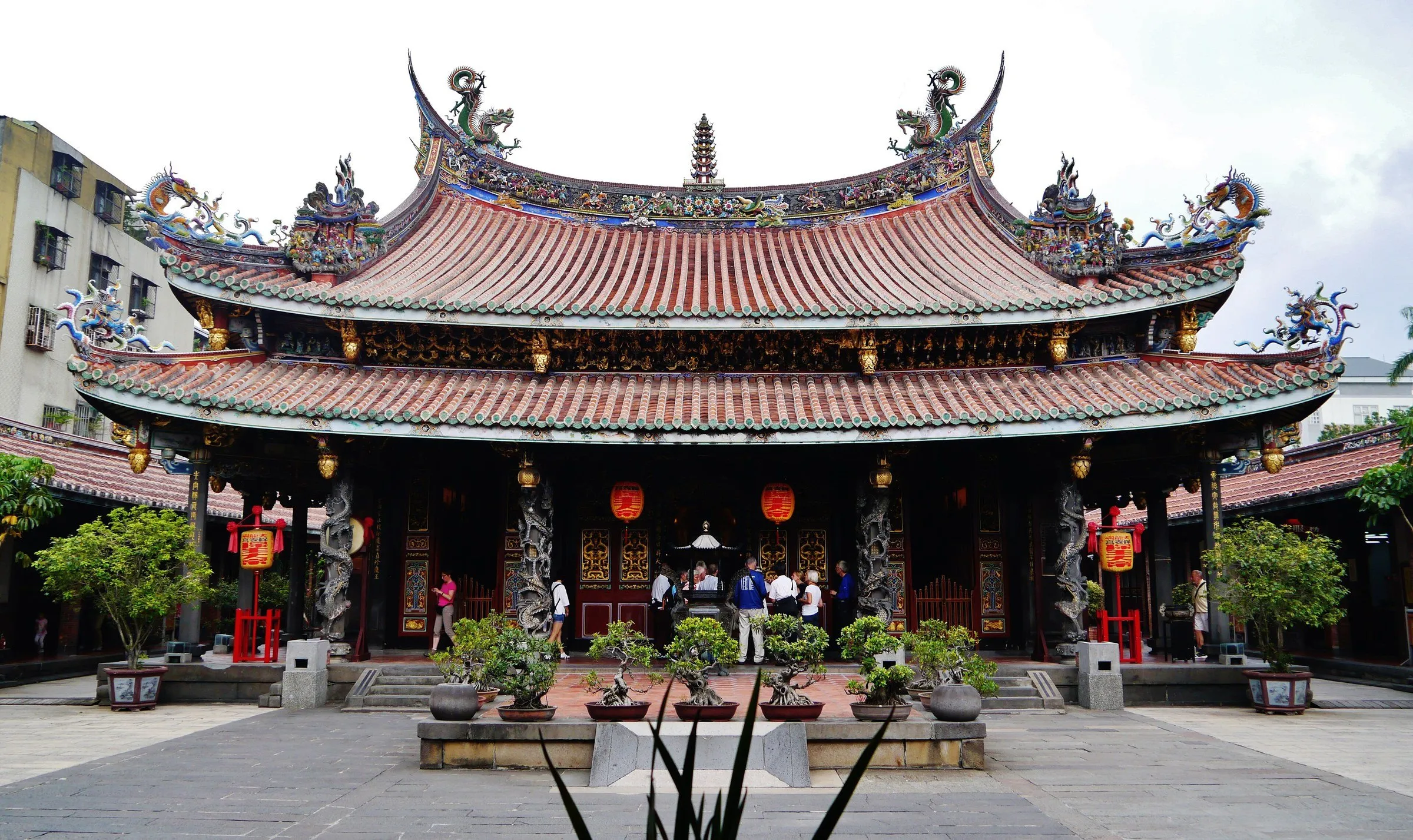 Salão principal do Templo Bao’an, com telhado ornamentado, colunas e vasos no pátio.