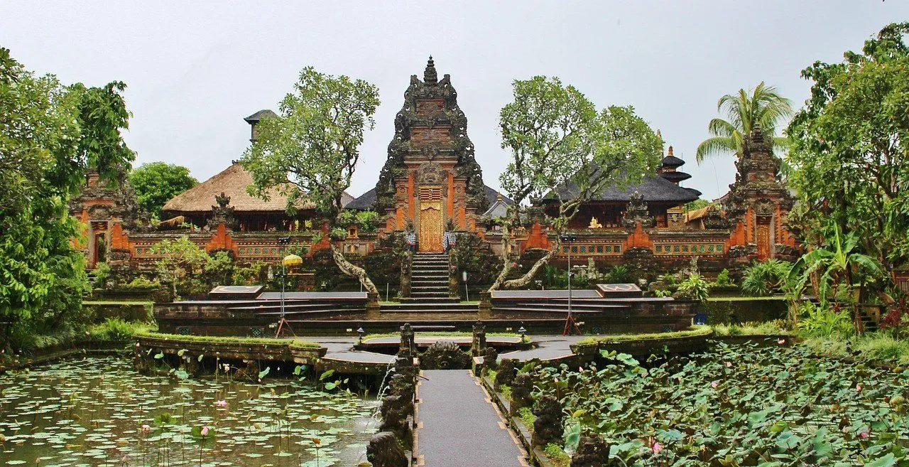 Caminho central entre lagos de lótus diante dos portais esculpidos do templo Saraswati, em Ubud.