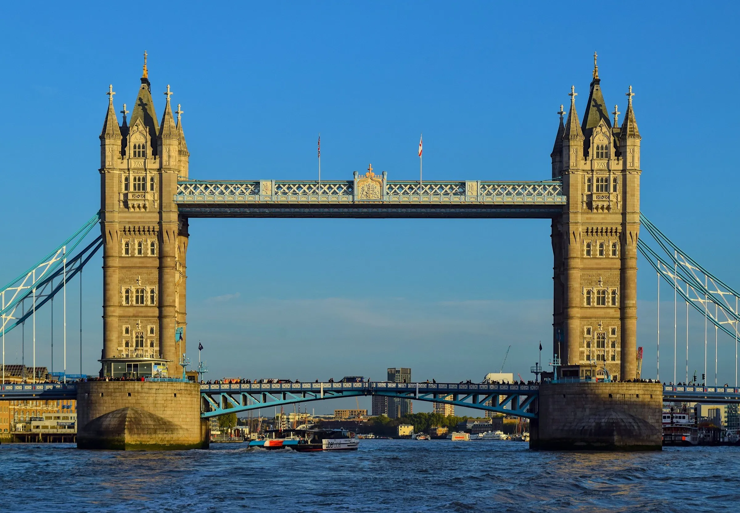 Tower Bridge vista de frente sobre o Tâmisa, com as duas torres de pedra e o céu azul limpo ao fundo.