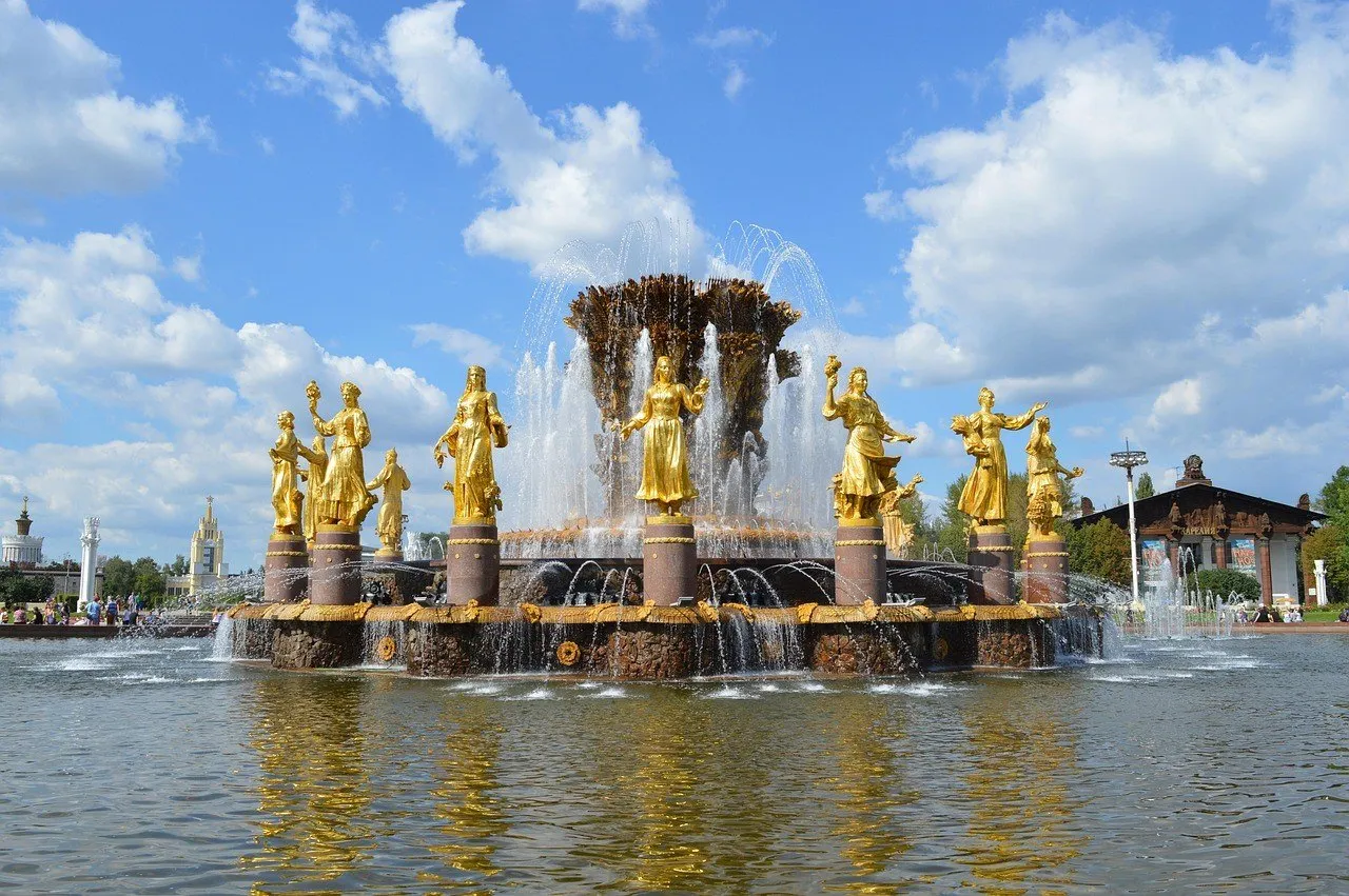 Esculturas douradas e jatos da Fonte da Amizade dos Povos, na VDNH de Moscou, sob céu azul.