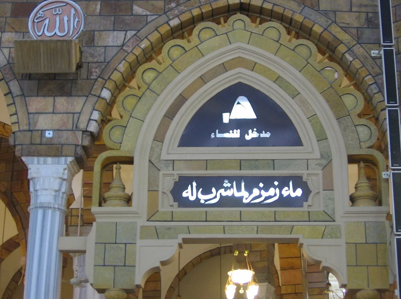 Arco decorado de uma passagem da Mesquita Sagrada, com placas em árabe que identificam a água de Zamzam.